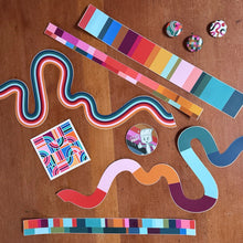 Load image into Gallery viewer, a flat lay of stickers. two are colorful, striped squiggle stickers. three are colorful barcode striped stickers. One sticker says "it's just paint" with a paintbrush giving a thumbs up. One sticker has a colorful maze design. Three colorful small button pins as well.